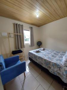 1 dormitorio con 1 cama y 1 silla azul en Casa Ribeirão da Ilha AEROPORTO, en Florianópolis
