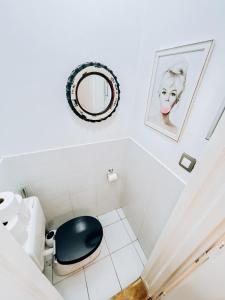 Baño blanco con aseo negro y espejo en Pd Residence, en Budapest