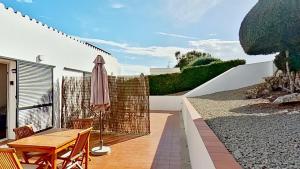 a patio with a wooden table and an umbrella at Apartamento Binibeca Nou Cami de Cavalls in Binibeca