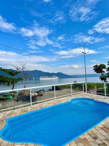 a blue swimming pool with a view of the water at Pousada Bonns Ventos in Ilhabela