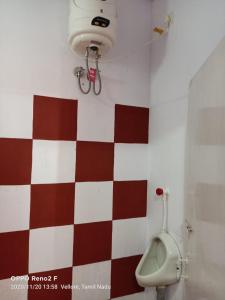 a bathroom with a urinal and a red and white checkered wall at John home stay in Yelagiri