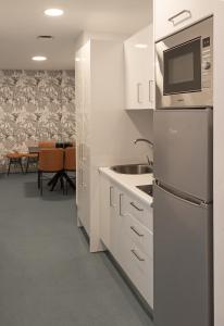 a white kitchen with a sink and a microwave at RK Farallón Canteras in Las Palmas de Gran Canaria