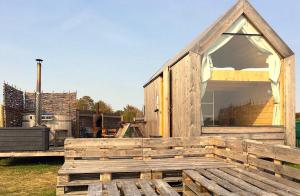 a wooden house with a large window on the deck at Lushna 8 Petite at Lee Wick Farm Cottages and Glamping in Clacton-on-Sea