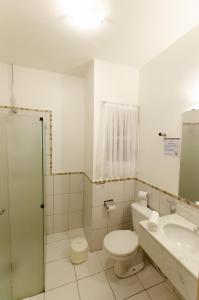 a bathroom with a toilet and a sink at Hotel Concord in Campo Grande
