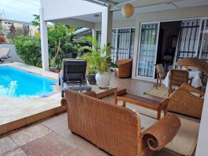 a patio with chairs and a grill next to a swimming pool at Lakaz du bonheur in Albion