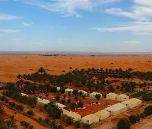 uma vista aérea de um deserto com árvores e edifícios em sunset luxury camp em Merzouga