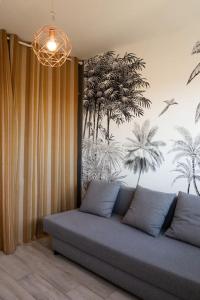 een bank in een kamer met een muurschildering van palmbomen bij Le Sauge - Beauzelle in Beauzelle