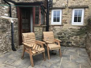 two wooden chairs sitting outside of a building at Cherry Tree Cottage, Aysgarth in Leyburn