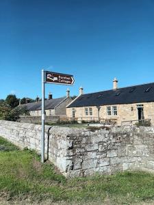 a street sign in front of a stone wall at Sandpiper Cottage in Alnham