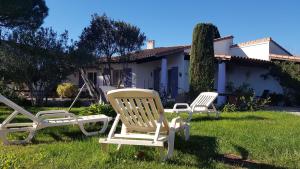 two chairs sitting in the grass in front of a house at Les Cyprés in Saintes-Maries-de-la-Mer