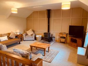 a living room with a couch and a tv at 4 Swallowholm Cottage in Langthwaite