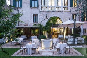 um restaurante com mesas e cadeiras brancas e um guarda-sol em Hotel Nani Mocenigo Palace em Veneza