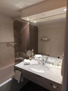 ein Badezimmer mit einem Waschbecken und einem großen Spiegel in der Unterkunft Hôtel La Reconce in Poisson