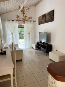 ein Wohnzimmer mit einem TV und einem Sofa in der Unterkunft Pousada Bonns Ventos in Ilhabela