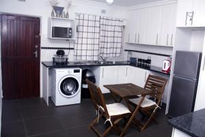 a kitchen with a washing machine and a table and chairs at 31 Miramar Cove in Port Edward
