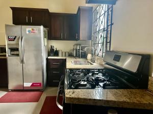 a kitchen with a stove and a stainless steel refrigerator at Dell's Exotic Haven, 2 bedrooms, 2 baths, pool, gym in Mammee Bay