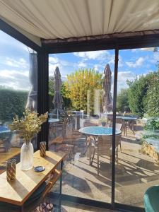 un patio con mesas y sillas y vistas al jardín en Hôtel La Reconce, en Poisson