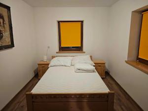 a small bedroom with a bed with two windows at Serce Beskidu Niskiego Myscowa in Krempna
