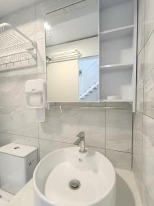 ein weißes Badezimmer mit einem Waschbecken und einem Spiegel in der Unterkunft Arte Cheras Duplex Near MRT 1 in Kuala Lumpur