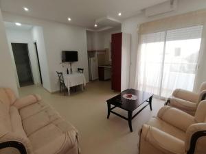 ein Wohnzimmer mit Sofas, einem Tisch und einem TV in der Unterkunft maison d'hôte familiale للعائلات فقط in Sousse