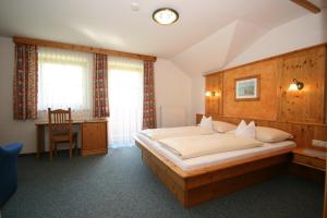 a bedroom with a large bed and a desk in it at Hotel Cafe' Hermann in Schladming