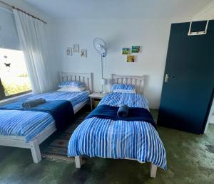 ein Schlafzimmer mit zwei Betten mit blauen und weißen Streifen in der Unterkunft Riverdance Cottage in Malgas
