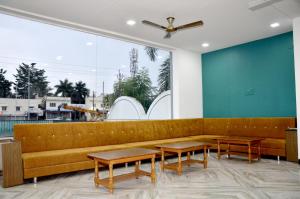 a lobby with a couch and tables and a large window at Hotel Adarsh in Aurangabad