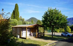 a small cabin in the grass with a car at CAMPING MUNICIPAL LA SAPINETTE in Quillan