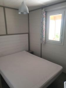 a bedroom with a white bed and a window at CAMPING MUNICIPAL LA SAPINETTE in Quillan
