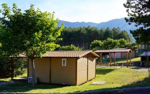 a small shed in a yard with a tree at CAMPING MUNICIPAL LA SAPINETTE in Quillan