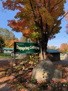 una señal para una universidad de primavera frente a un árbol en Dayspring Cottages, en Emsdale