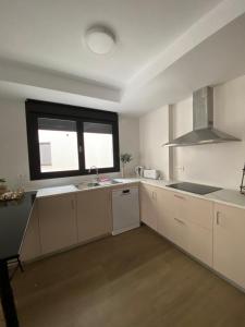 uma cozinha com armários brancos, um lavatório e uma janela em Apartamento Isabel em Caravaca de la Cruz