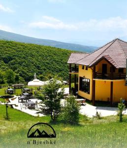 ein gelbes Haus mit einem Tisch und Stühlen auf einem Feld in der Unterkunft N'Bjeshke te guri i zi in Prizren