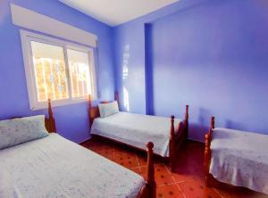 a blue room with two beds and a window at Dar Khairoun with Balcony in Chefchaouene
