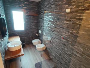La salle de bains est pourvue de 2 toilettes et d'un mur en pierre. dans l'établissement residence Sant'Anna i4MORI, à SantʼAnna Arresi 24 autres photos