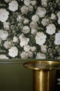 a floral wallpaper with white flowers on a wall at Maison Prieuré 
