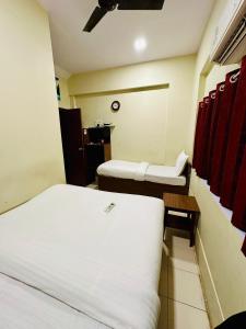 a hotel room with two beds and a table and a bed at Amber Guest House in Mumbai