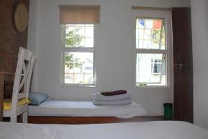 a bedroom with two windows and a bed and a chair at KAJI HOME in Pātan