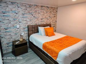 a bedroom with a bed with a brick wall at Hotel Kristal Ferial in Bogotá