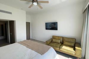 a bedroom with a bed and a couch and a ceiling fan at Beautiful Penthouse with private elevator in Hard Rock Golf in Punta Cana