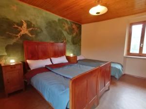 ein Schlafzimmer mit einem Bett und einem Wandgemälde in der Unterkunft Casa d'arte in the mountains on Lake Orta - 16 per in Quarna Sotto