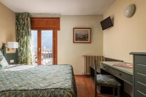 a bedroom with a bed and a desk and a window at Hotel Sant Jordi by ALEGRIA in Andorra la Vella