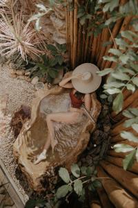 a woman with a hat sitting in a tree stump at Vila Cerrado in Alto Paraíso de Goiás