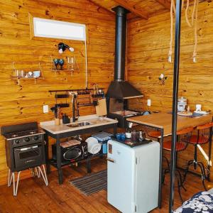 uma cozinha com um fogão e um lavatório numa cabina em O Chalé Encantado - Rancho Queimado em Rancho Queimado