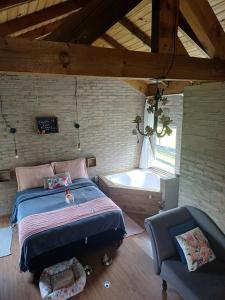 a bedroom with a bed and a tub and a chair at O Chalé Encantado - Rancho Queimado in Rancho Queimado