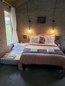 uma cama grande num quarto com uma parede de tijolos em O Chalé Encantado - Rancho Queimado em Rancho Queimado