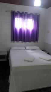 um quarto com 2 camas e uma janela roxa em POUSADA RECANTO DOS PASSAROS em Pirenópolis