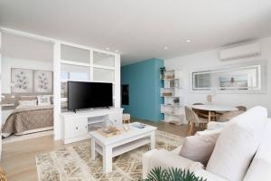 ein Wohnzimmer mit einem Sofa und einem TV in der Unterkunft Stylish Beachfront Escape . Steps to Beach . Wifi in Portimão