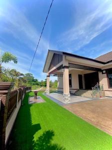 a house with a green lawn in front of it at Homestay Wakaf Bharu Tumpat in Wakaf Baharu