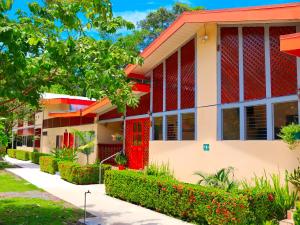 a building with red doors and a yard at Villas Allen Puerto Viejo in Puerto Viejo